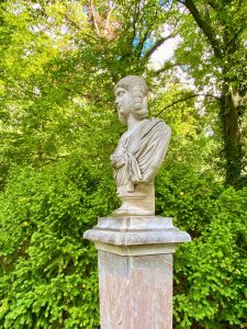 Büste auf einem Steinsockel im parkähnlichen Garten von Schloss Lindstedt, Potsdam